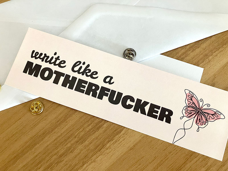 A bookmark with the words Write Like a Motherfucker on it